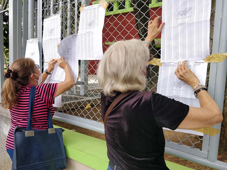 People look at lists on a wall.