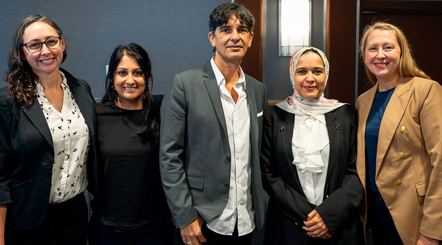 Five people smile facing the camera.