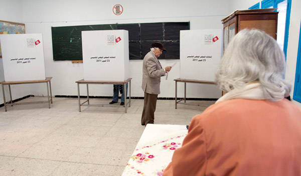 A man studies the ballot before heading behind the booth to make his selection.