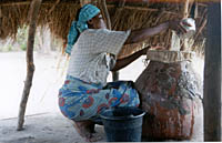 A Togolese woman in a village strains her family's drinking water through a nylon filter to prevent them from contracting Guinea worm disease.